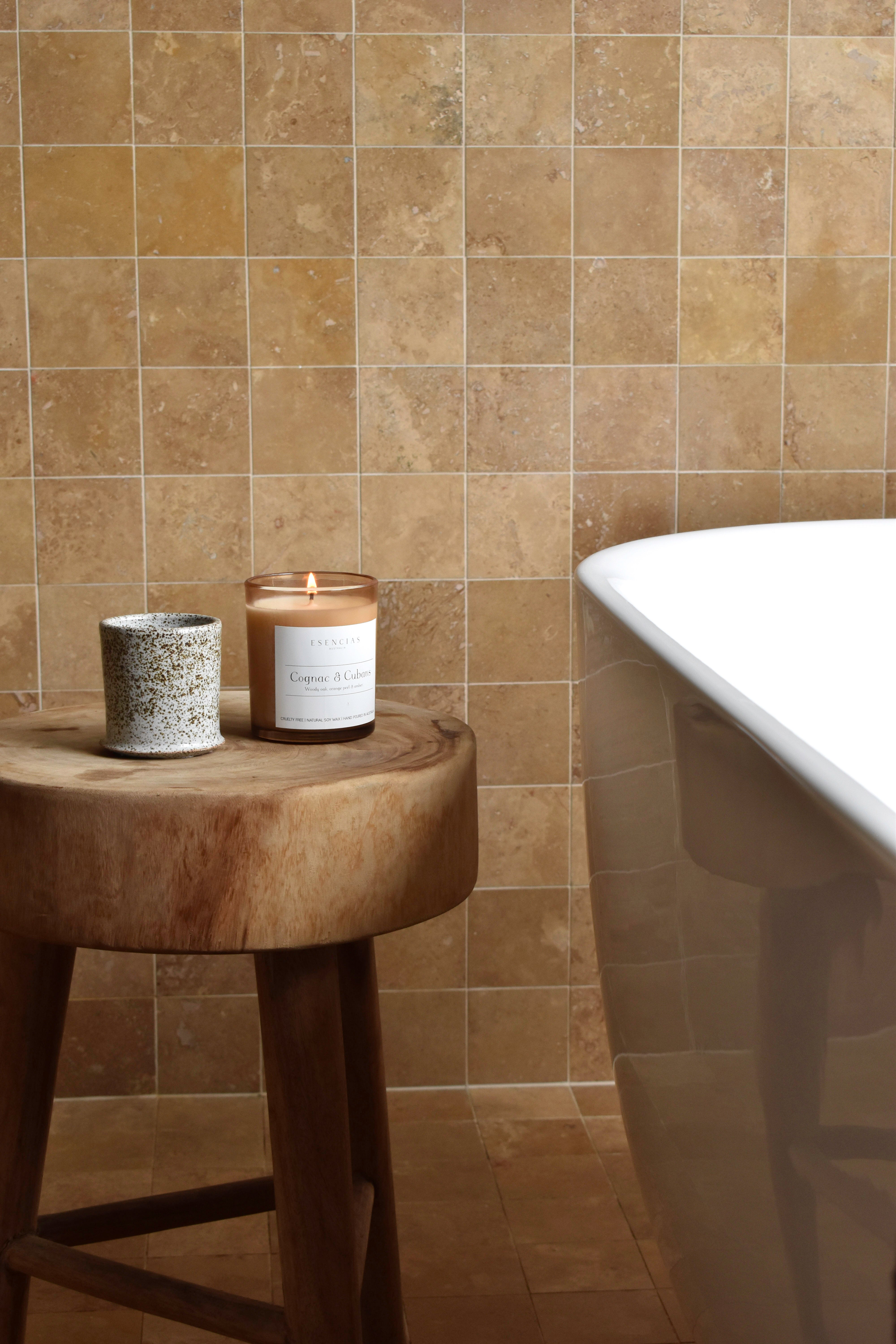 Cognac & Cubans candle in amber jar styled in a bathroom lifestyle setting, radiating warmth and a luxurious atmosphere.