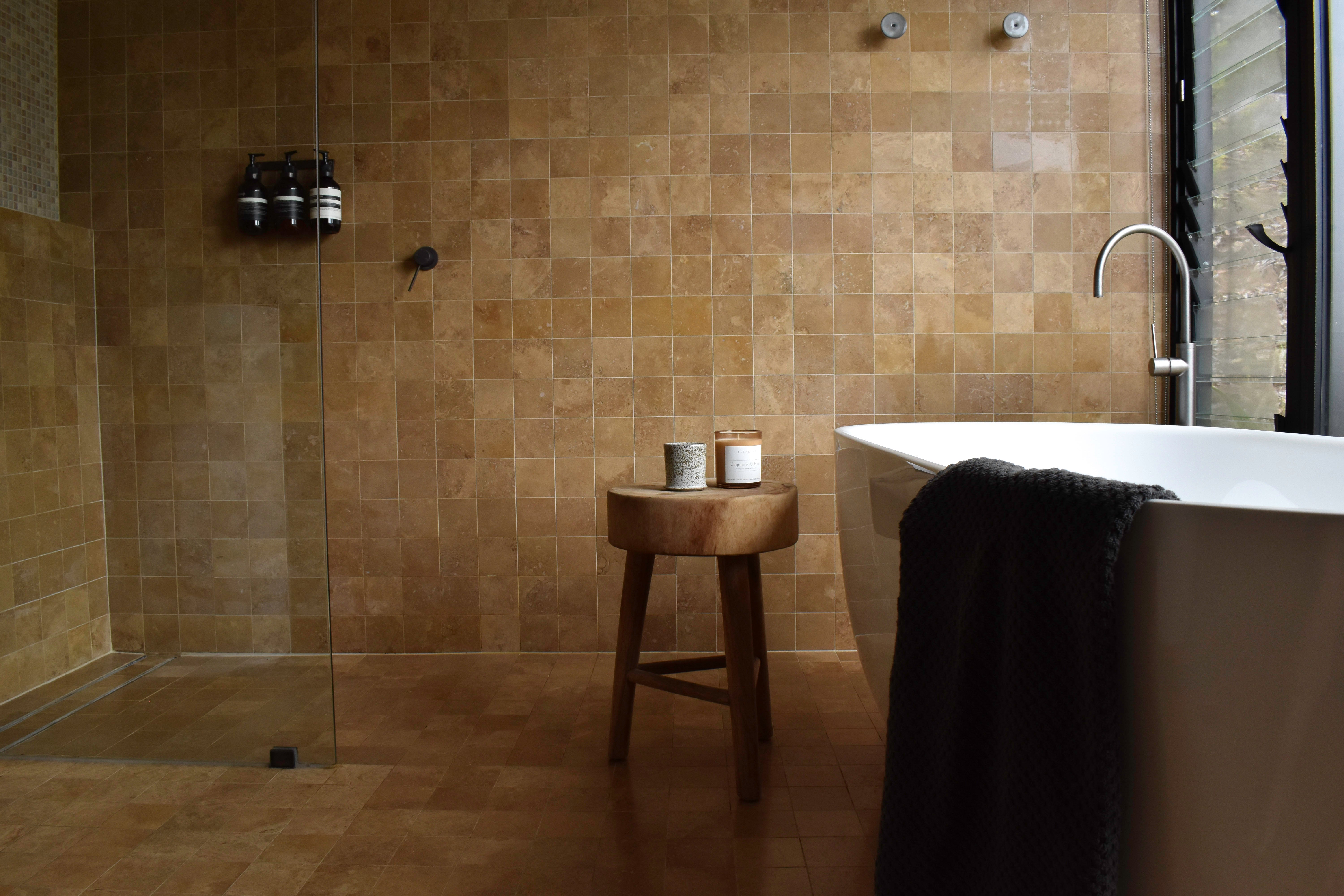Cognac & Cubans candle in amber jar shown in a wider bathroom lifestyle setting, highlighting a cozy and luxurious self-care space.