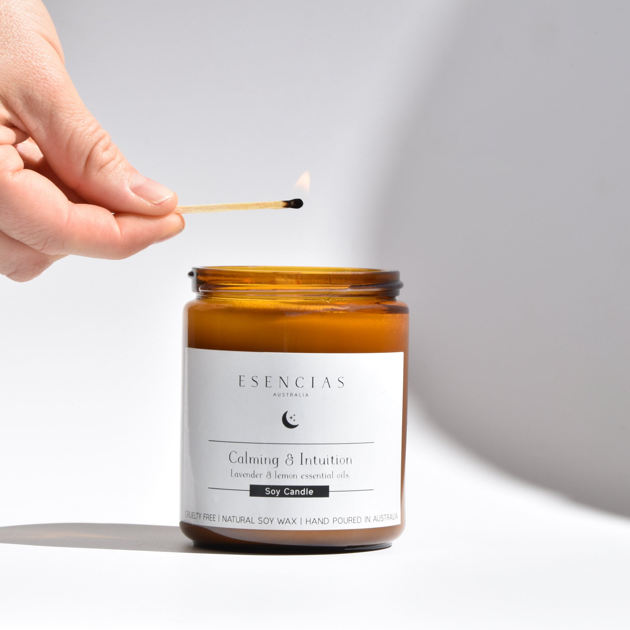 Lighting the Esencias Calming and Intuition soy candle to invite peace and clarity