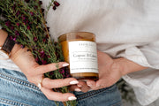 Cognac & Cubans Soy Candle Signature Range model shot with dark flowers. 