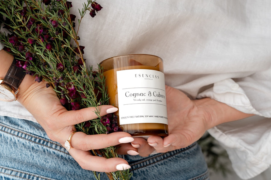 Cognac & Cubans Soy Candle Signature Range model shot with dark flowers. 