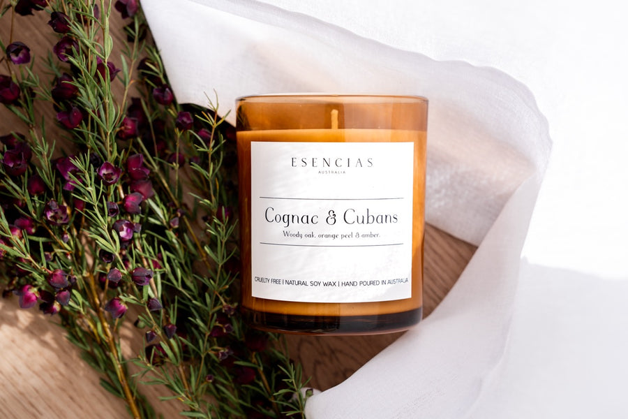 Cognac & Cubans Soy Candle Signature Range close up product image with flowers and timber. 
