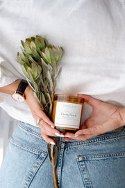 Ebony Peach Soy Candle Signature Range model shot with flowers. 