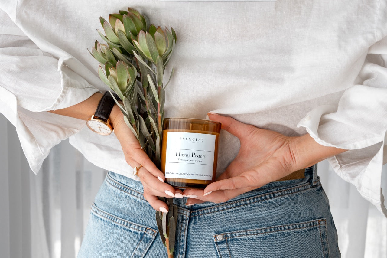 Ebony Peach Soy Candle Signature Range model shot with flowers, playful and fun. 