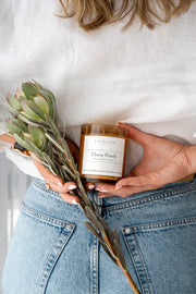 Ebony Peach Soy Candle Signature Range model shot with playful angles and flowers. 