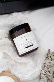 Jar of 'Love & Peace' soy candle on a soft white fabric background