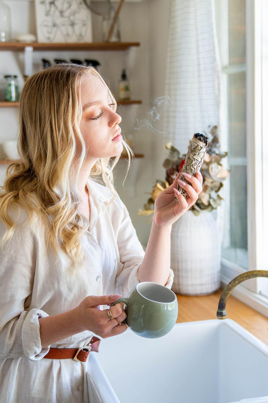 Model with our Sage Smudge stick in kitchen clearing energy of home. 