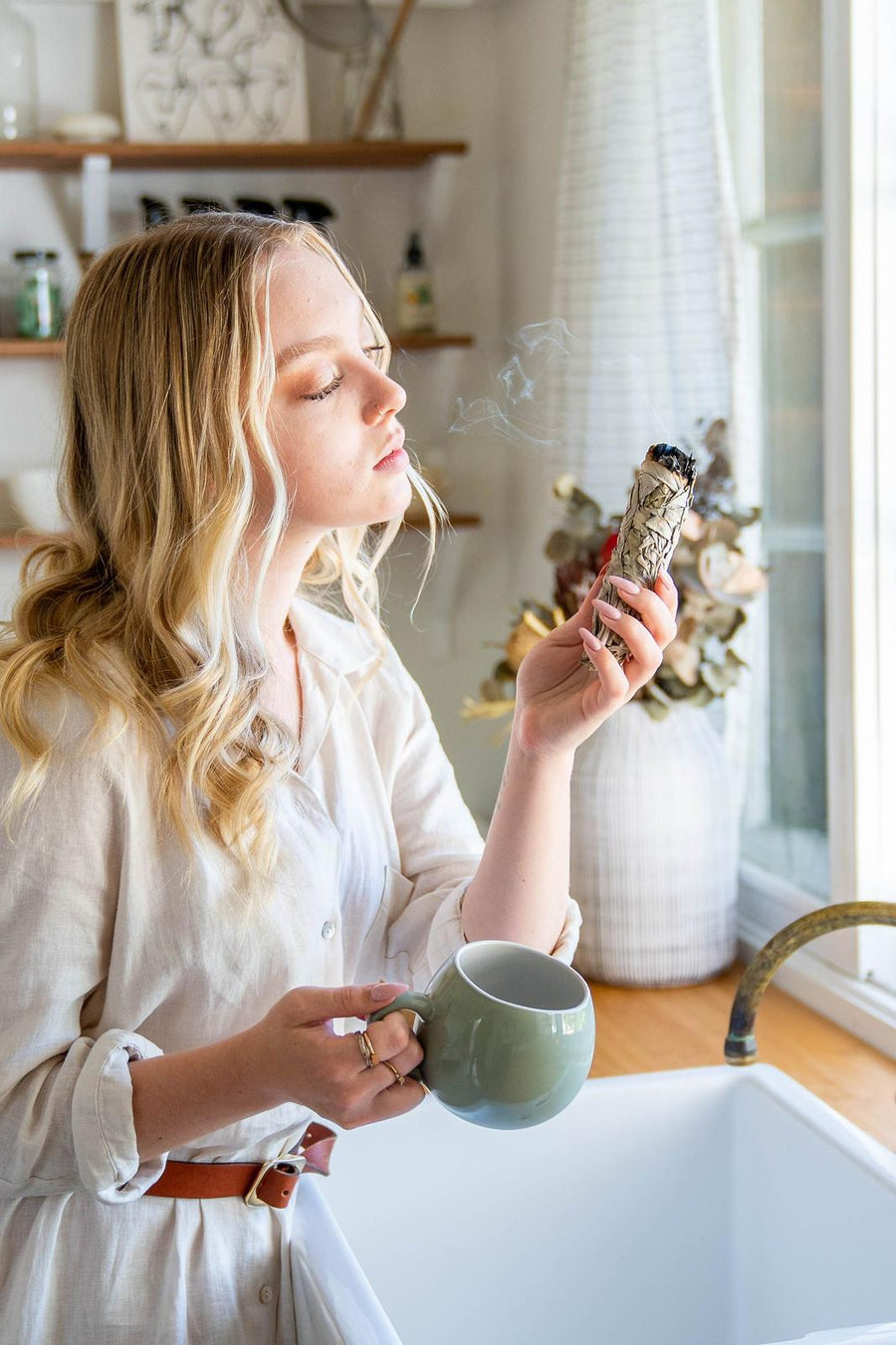 Model with our Sage Smudge stick in kitchen clearing energy of home. 