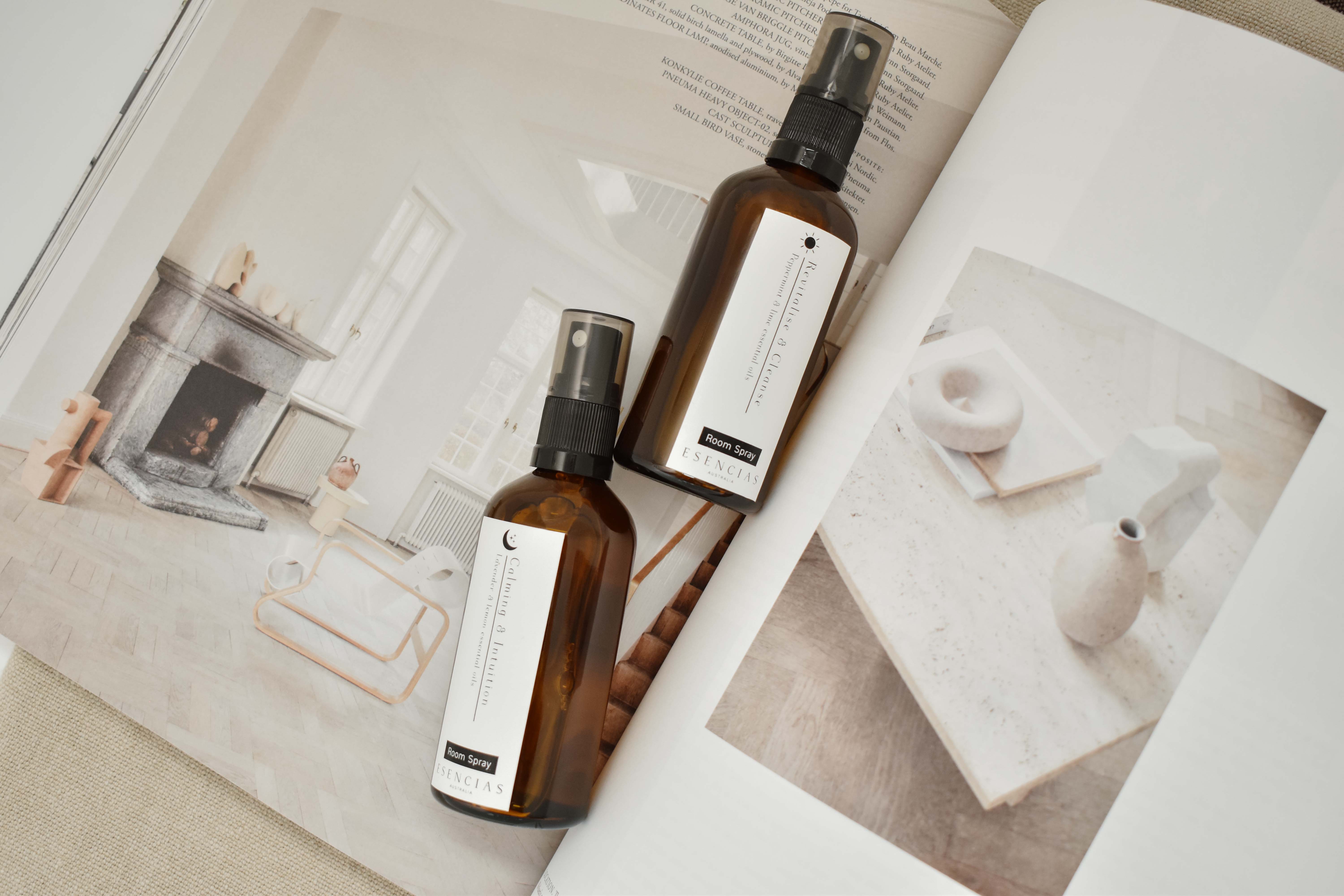 Esencias Revitalise & Cleanse and Calming & Intuition room sprays styled on an open magazine page