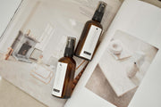 Esencias Revitalise & Cleanse and Calming & Intuition room sprays styled on an open magazine page