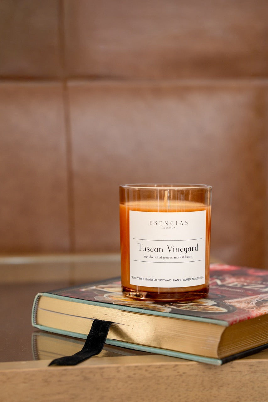 Tuscan Vineyard Signature soy candle styled on a book.