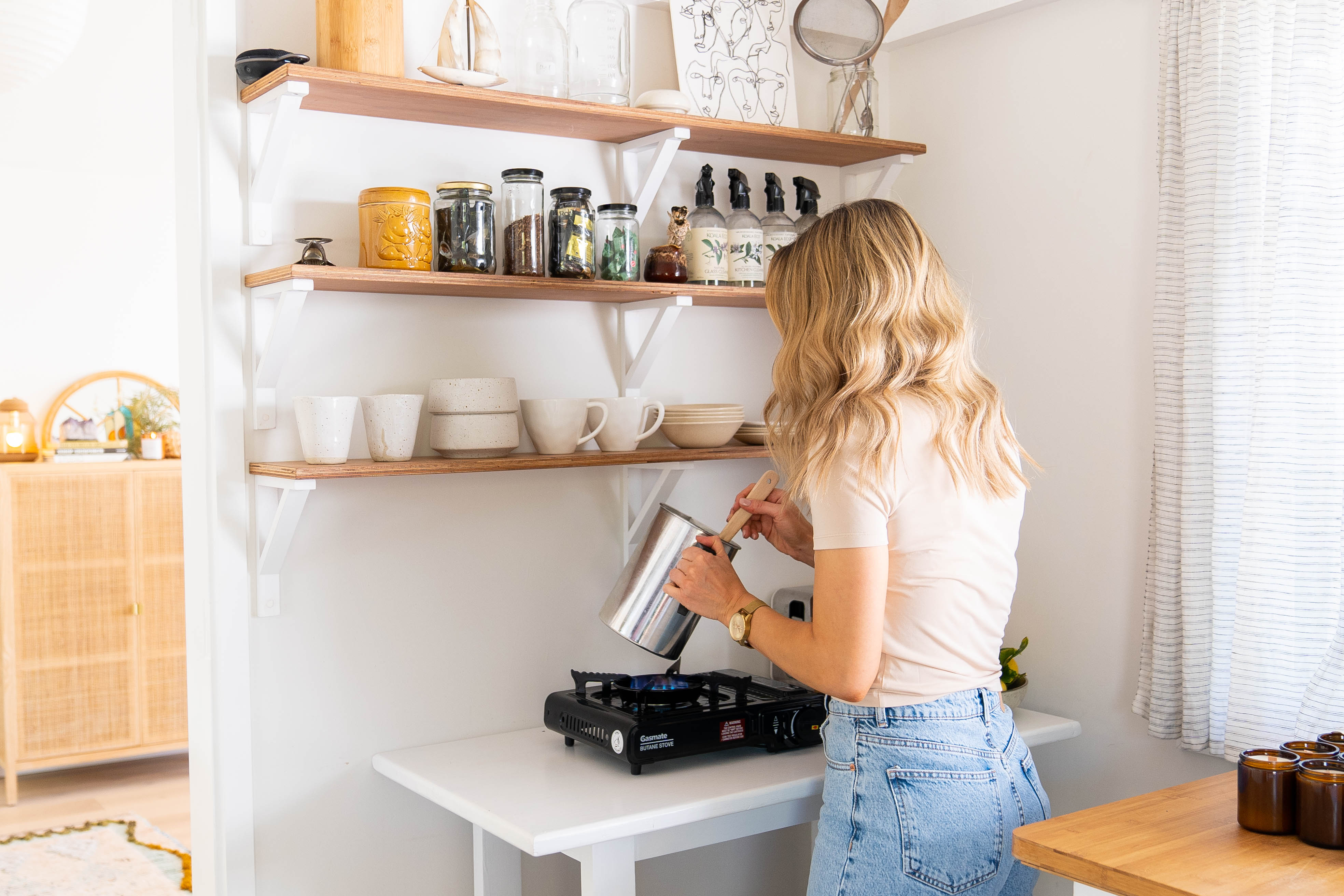 Image of Dominique, founder of Esencias, gently heating candle wax in preparation for pouring, capturing her artisanal process and care in candle making.