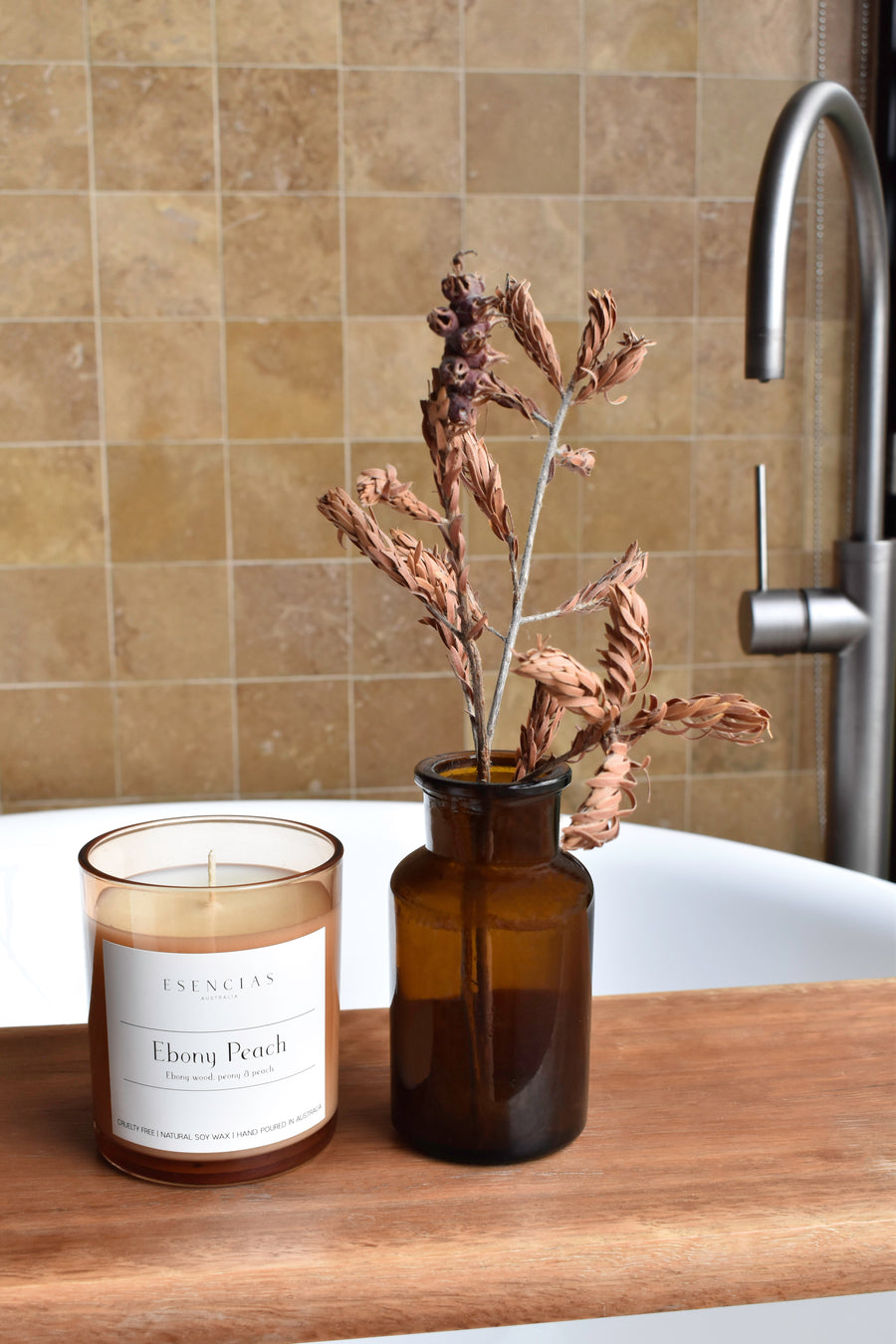 Ebony Peach candle in amber jar styled in a bathroom setting, creating a warm and luxurious atmosphere.