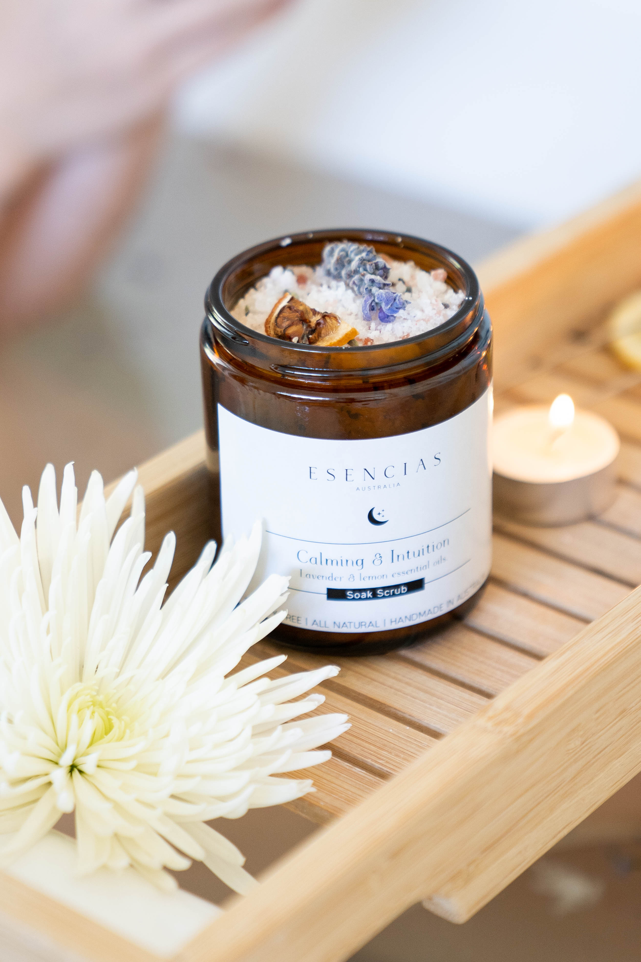Esencias Calming & Intuition soak scrub resting on a wooden tray over a bath