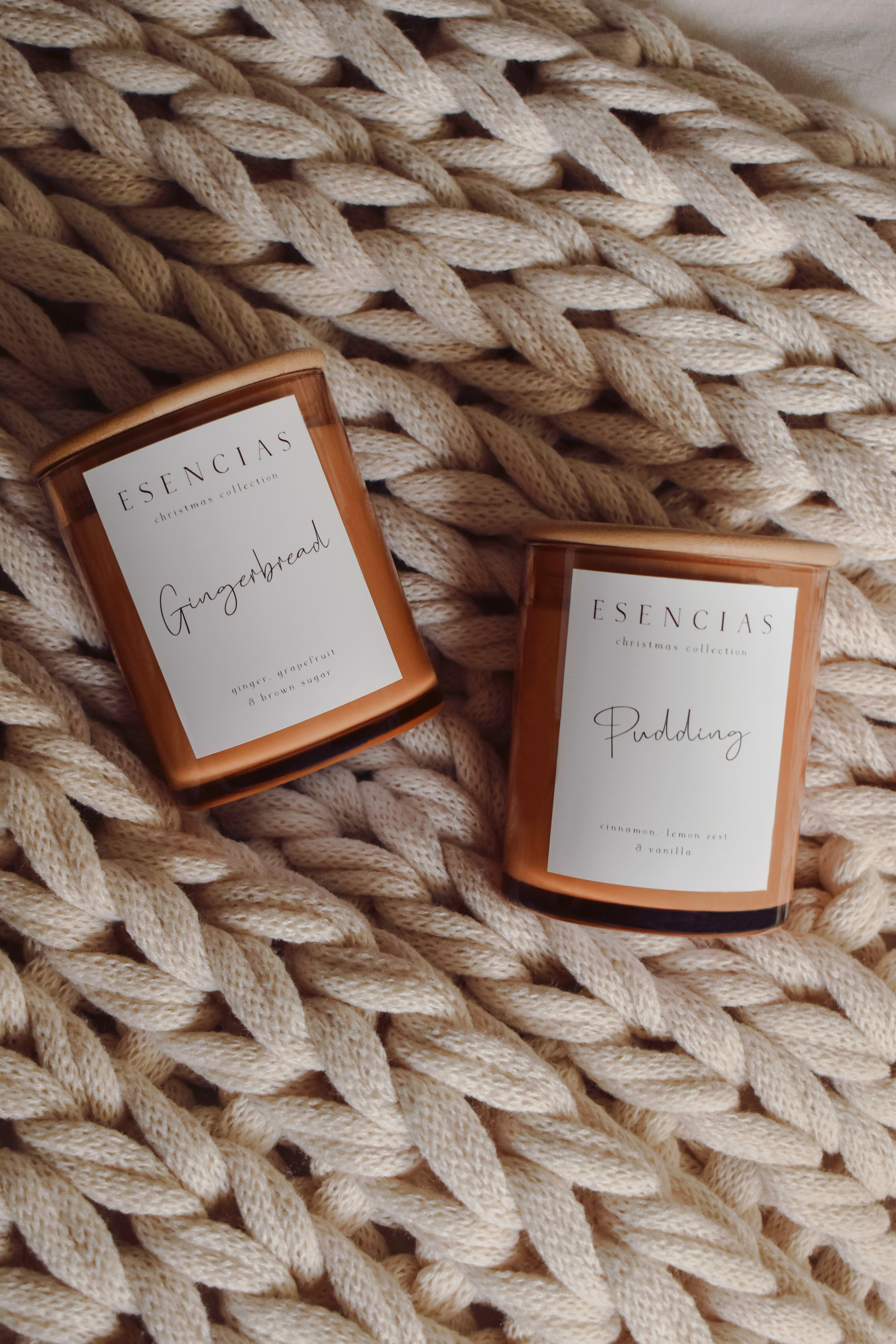 Gingerbread and Christmas Pudding soy candles nestled on a soft wool blanket, evoking warmth and cosy seasonal comfort.