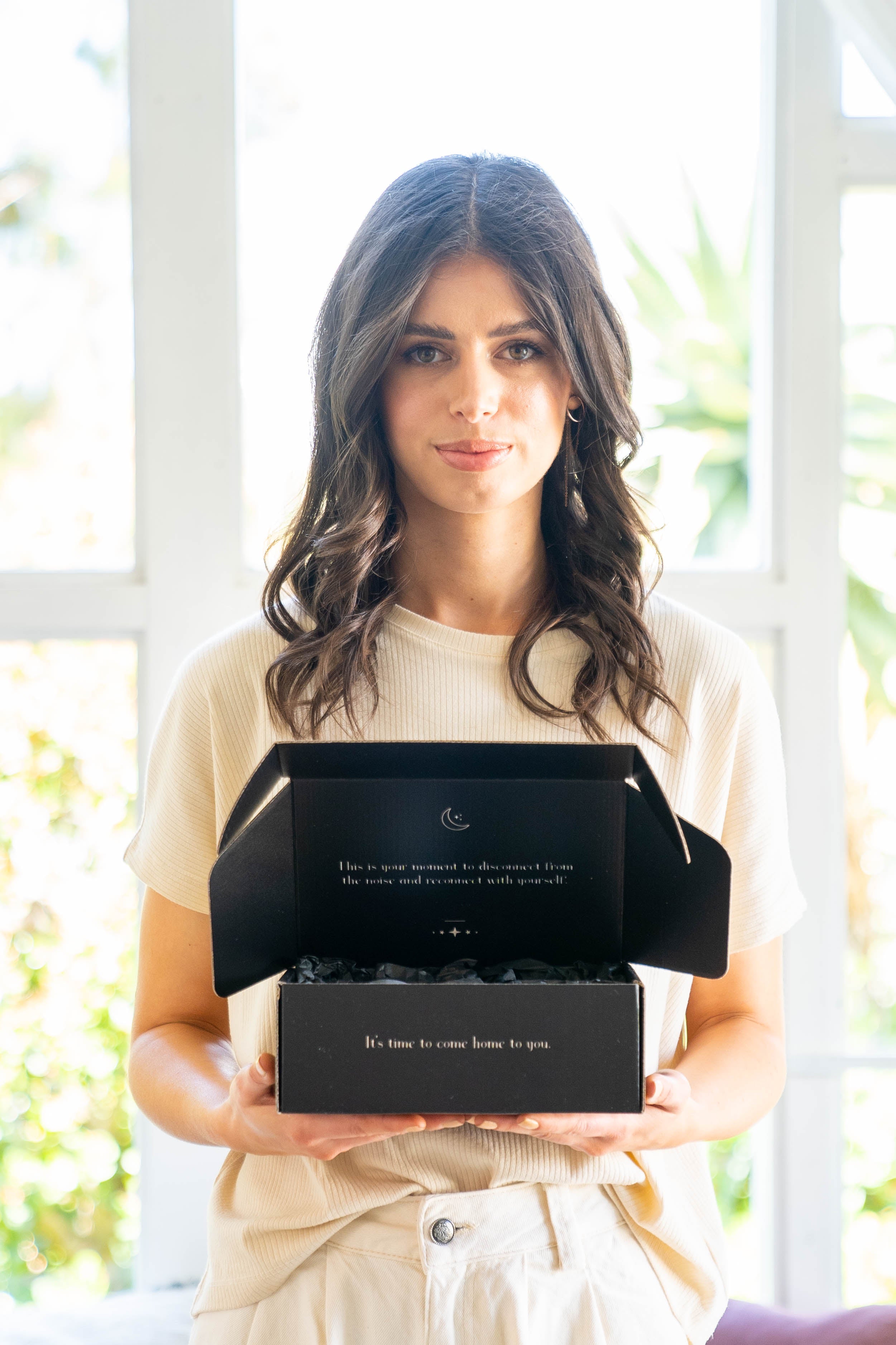 Model holding a bundle in its packaging in a natural lifestyle setting, highlighting the product’s elegance and thoughtful presentation.