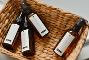 Room sprays arranged in a natural cane basket styled in a lifestyle setting, evoking an organic and calming atmosphere.