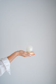 Hand holding selenite sphere with LED lamp against a plain background
