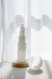 Selenite sphere and selenite tower together next to sheer curtian