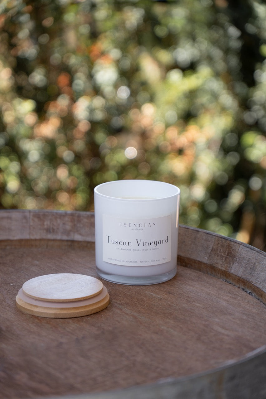 Tuscan Vineyard candle from the Coastal Collection styled outdoors on a wine barrel, evoking rustic elegance and sunlit vineyard vibes.
