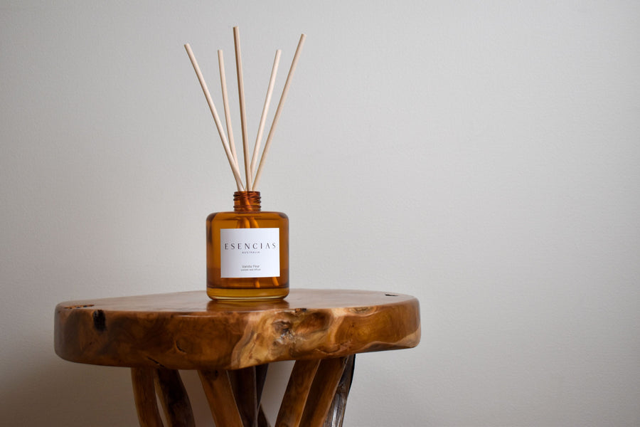 Vanilla Pear reed diffuser in amber jar styled on natural timber surface, evoking warmth and rustic elegance in a product-focused image.
